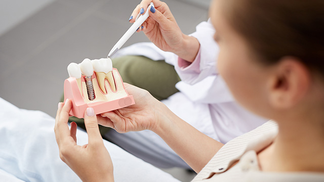 A dental professional uses a device to examine a patient's teeth during a dental appointment.