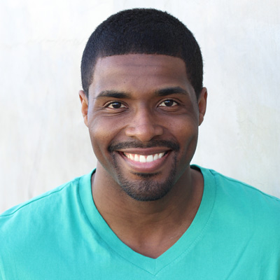 A man and woman are seated together, smiling at the camera.