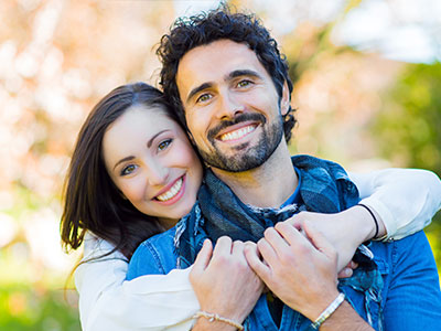 The image shows a man and a woman embracing each other with smiles on their faces; they appear to be posing for a portrait.